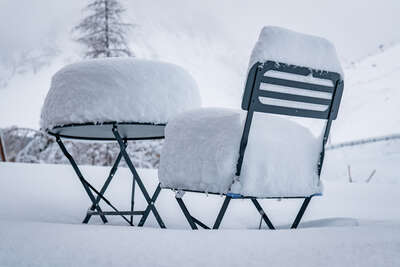 Table et chaise recouvertes de neige fraîche à Tignes
